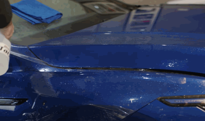 A close-up view of the PPF being peeled and adjusted on a blue vehicle?s fender during installation.